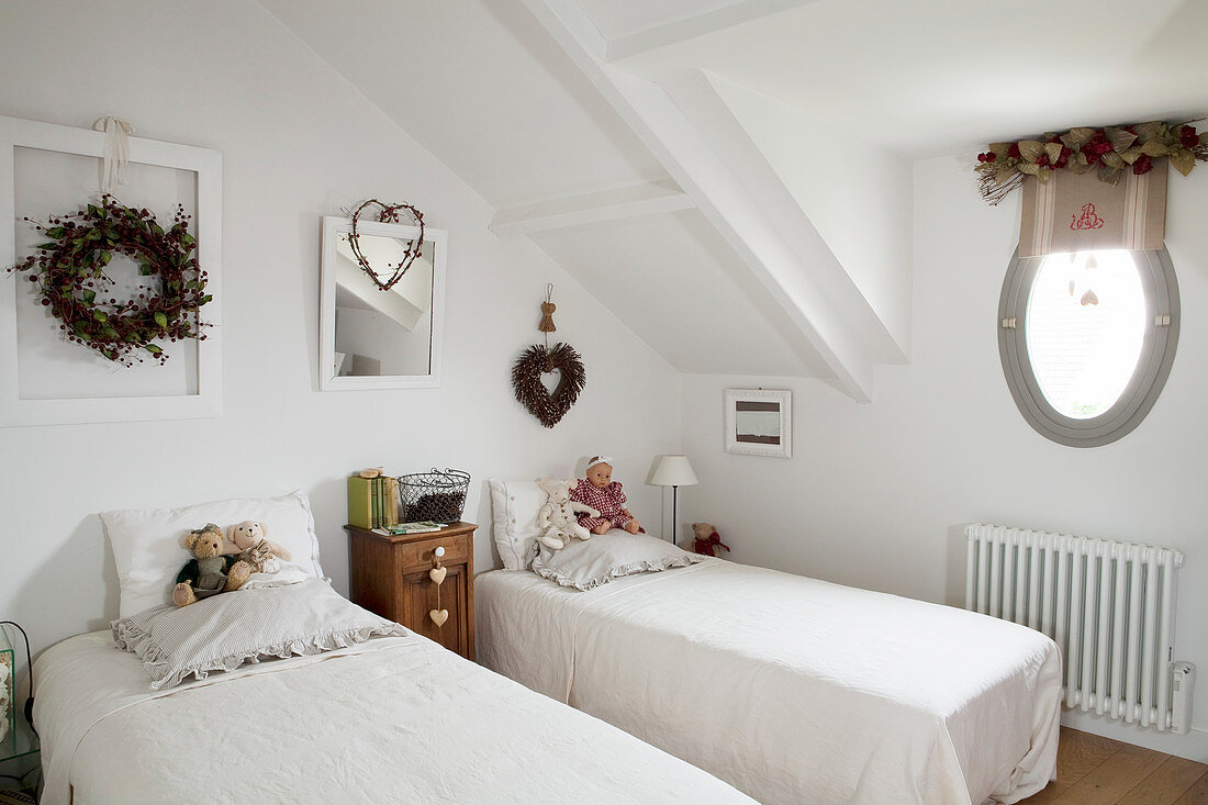 Old teddy bears and doll on twin beds in vintage-style attic bedroom