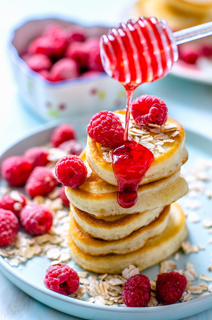 A stack of pancakes with raspberries and raspberry sauce