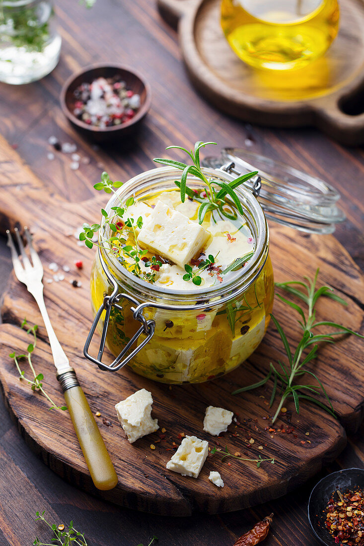 Marinierter Feta in Olivenöl mit frischen Kräutern im Glas