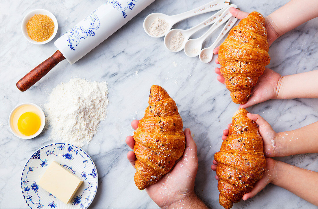 Croissants, baking ingredients with father and kids hands holding fresh croissant