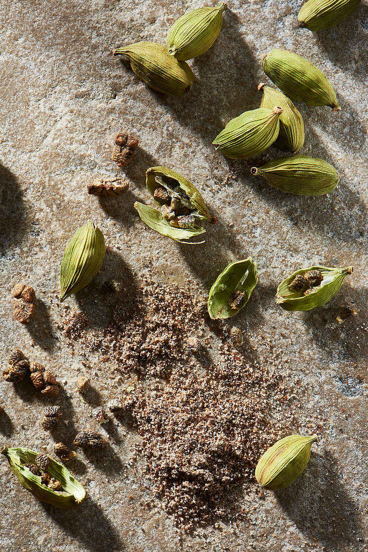 Cardamom pods with ground cardamom on stone from overhead