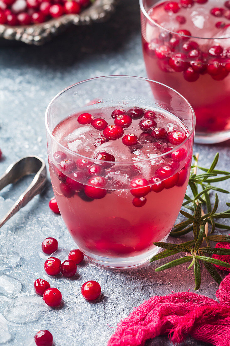 Refreshing drink with cranberries, ice and rosemary