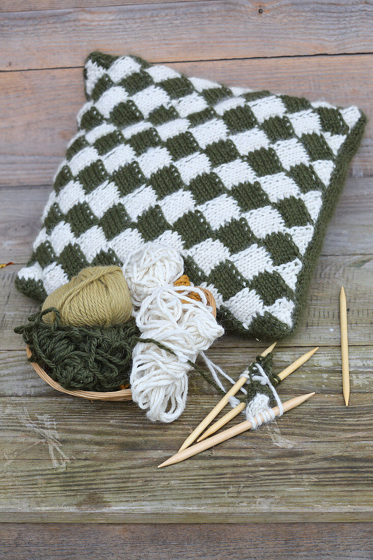 Cushion with hand-knitted cover, wool and knitting needles