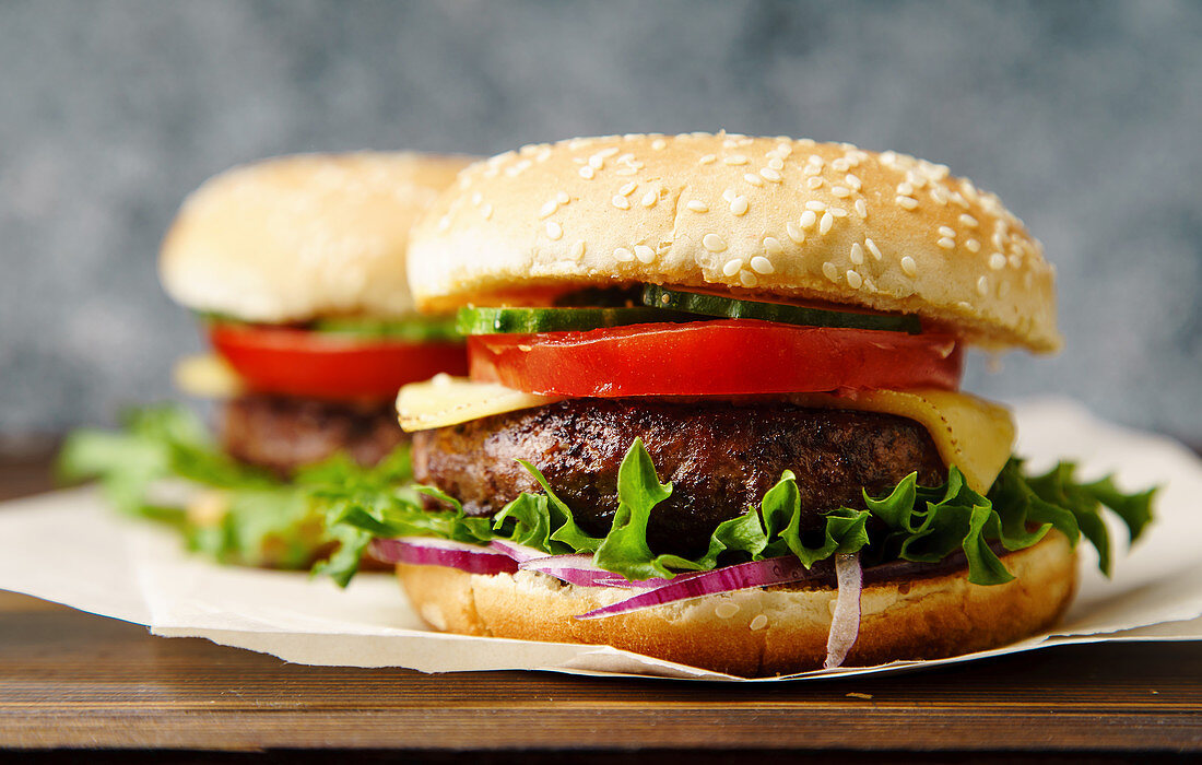 Grilled burgers with tomato, cheese, onion, cucumber and lettuce leaves
