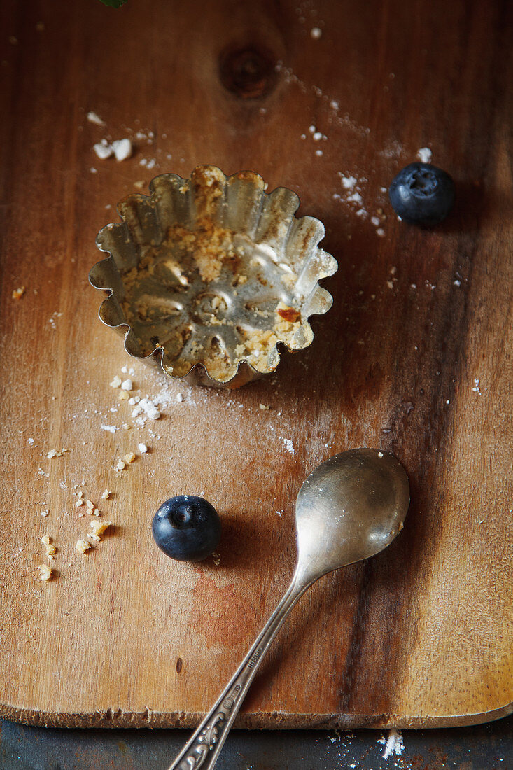 An empty tart case and blueberries on a wooden background