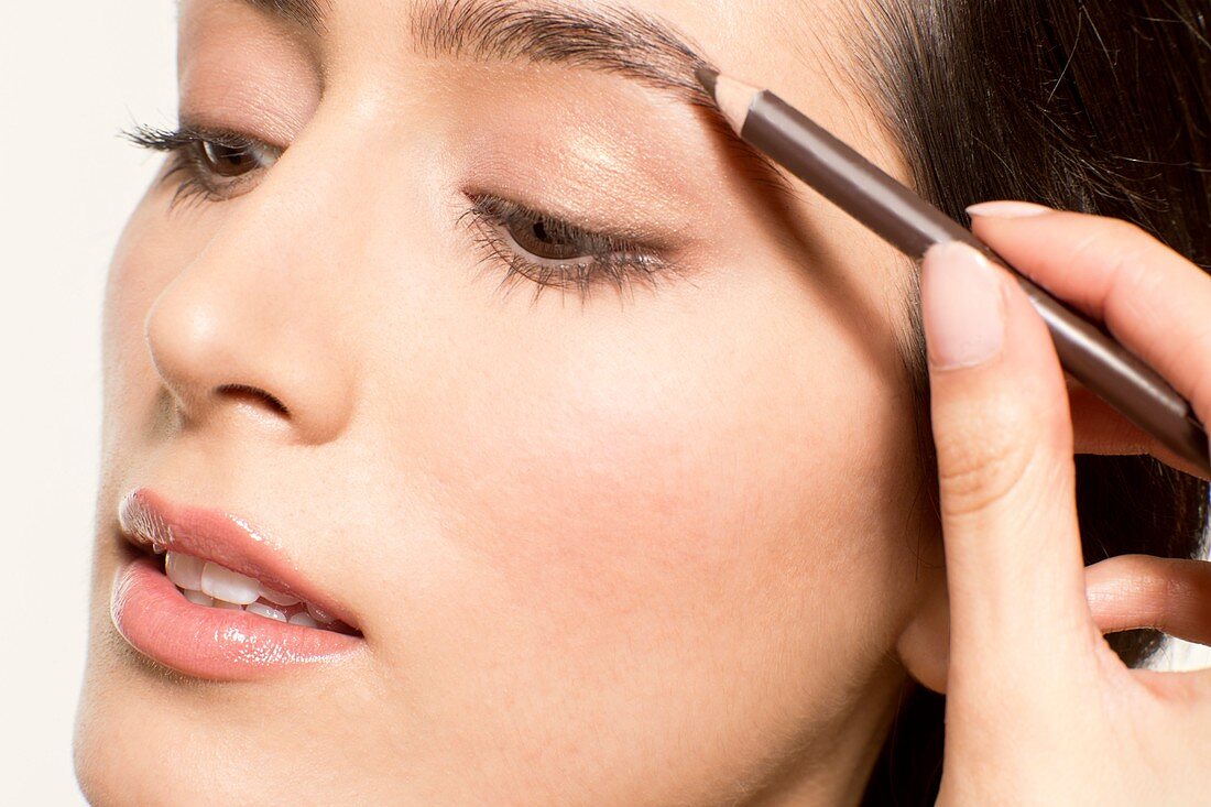 Woman applying eyebrow pencil