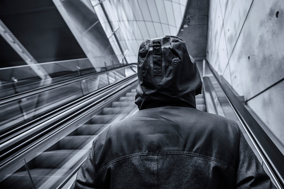 Hooded person on escalator