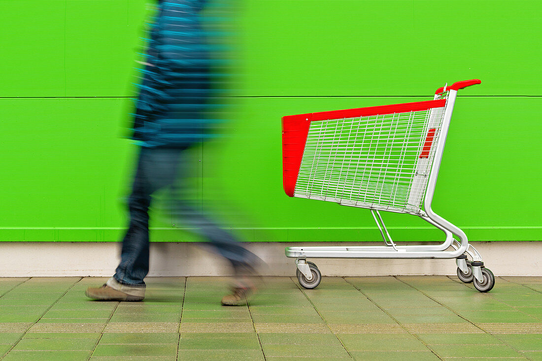 Man walking by empty shopping trolley