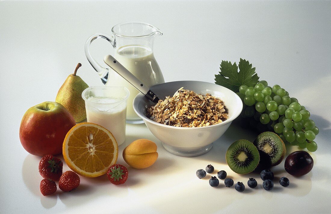 Ein Schälchen mit Müsli, Deko: Frisches Obst, Milch, Joghurt