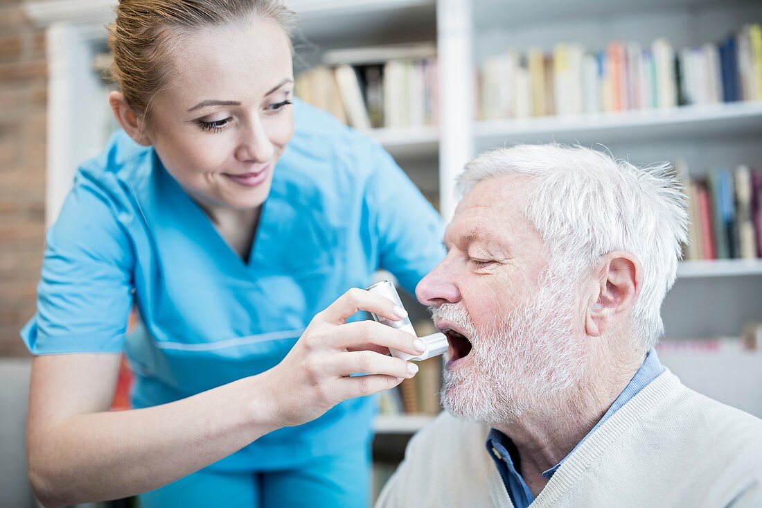 Carer helping senior man with inhaler