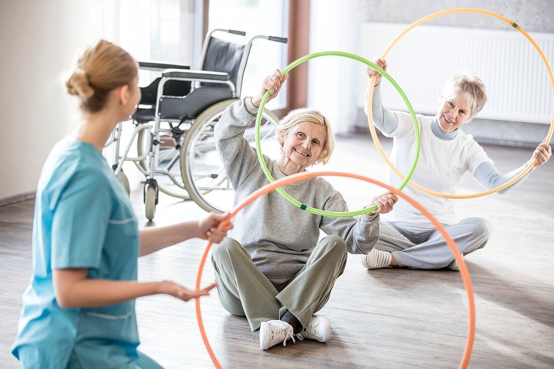 Physiotherapist with women holding plastic hoops