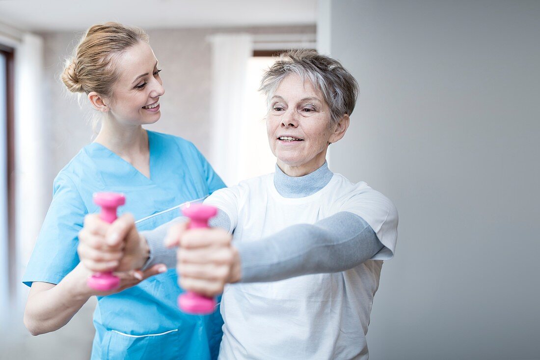 Woman holding hand weights with physiotherapist