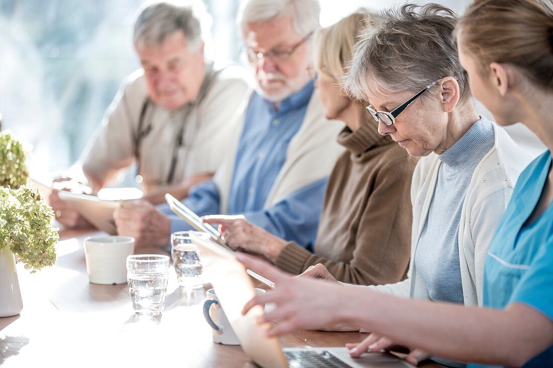 Seniors using tablets with carer