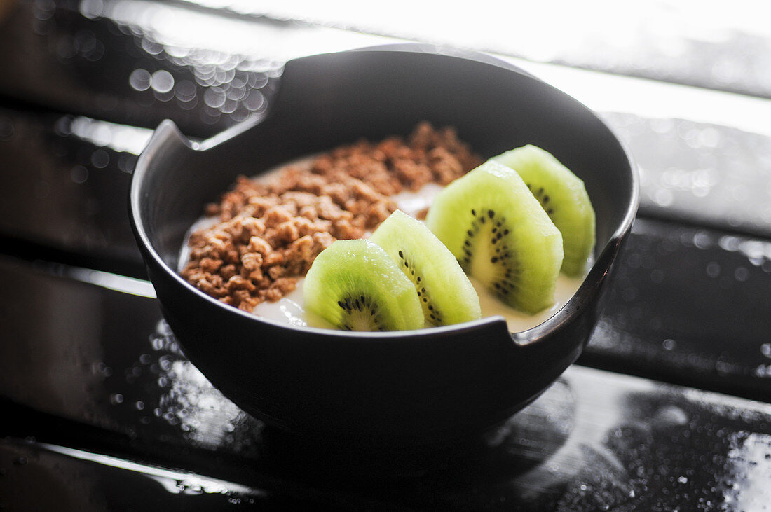 Joghurt mit Müsli und Kiwi in schwarzer Schale