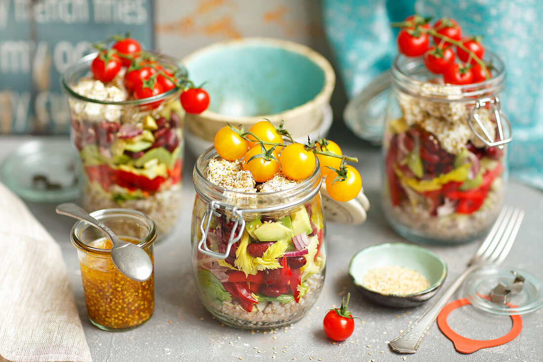 Geschichteter Salat im Glas mit Buchweizen, Bohnen, Avocado, Gemüse und Feta