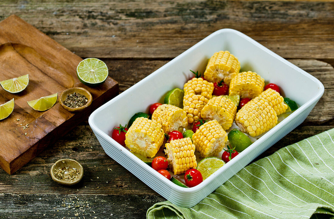 Roasted corn on the cob with cherry tomatoes and limes