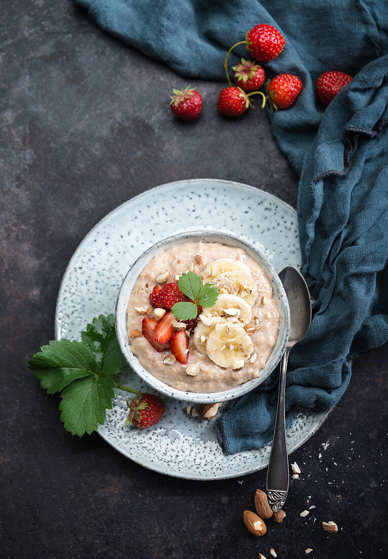 Veganer Dinkel-Porridge mit Mandeldrink, Bananen, Erdbeeren und Mandeln