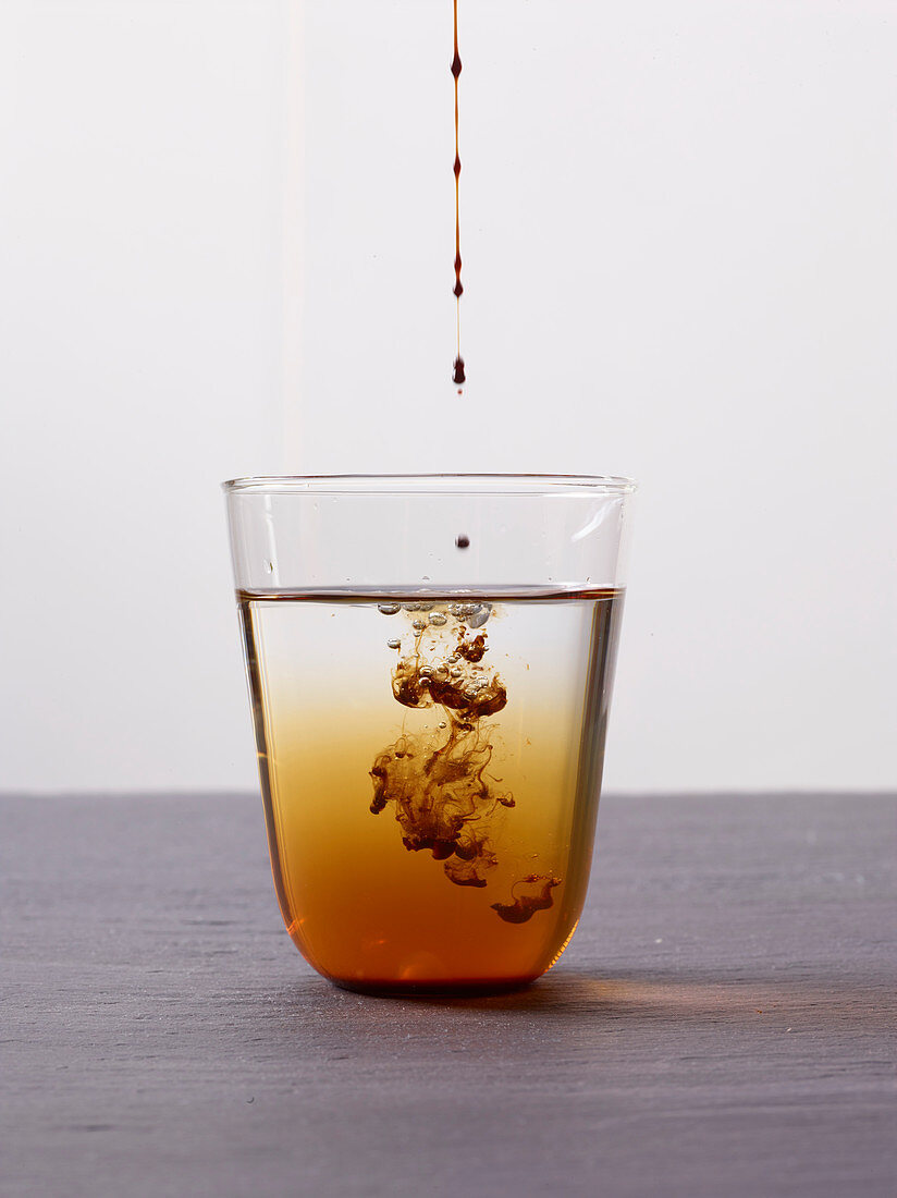 Tamarindensirup tropft in ein Wasserglas