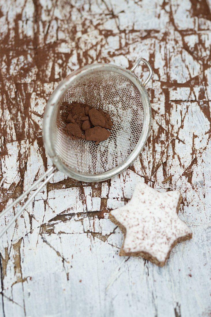 Cocoa powder in a sieve with a gingerbread star