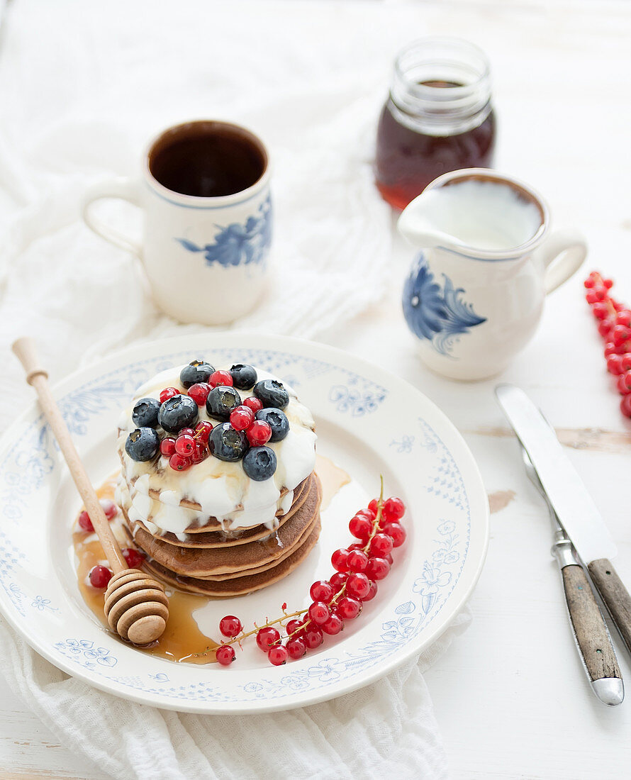 Buckwheat pancakes with fresh berries, honey, sour cream and cup of coffee