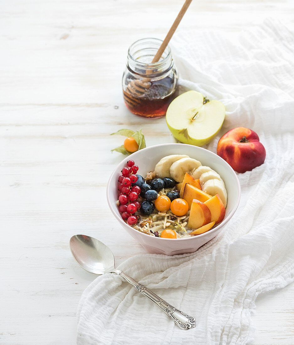 Bowl of oat granola with yogurt, fresh berries, fruit and honey