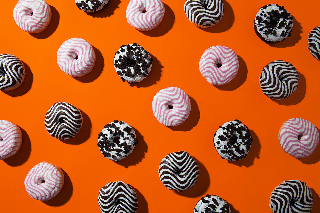 Verschiedene Donuts auf orangefarbenem Hintergrund