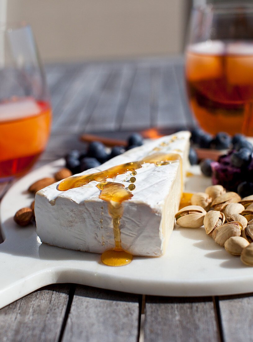Cheeseboard with brie drizzled with honey, blueberries, almonds and pistachios