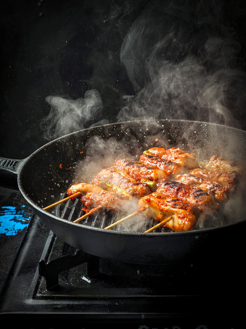 Steaming chicken skewers in a grill pan
