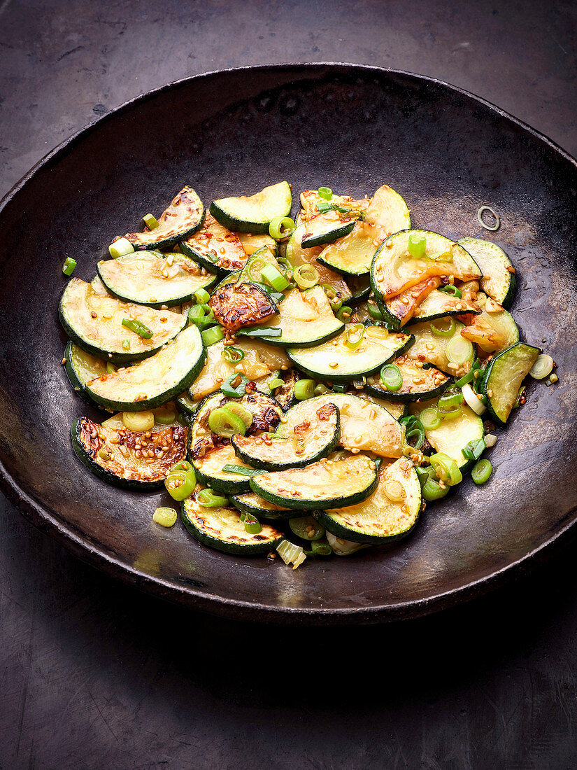 Fried courgette slices with spring onions in a wok (Asia)