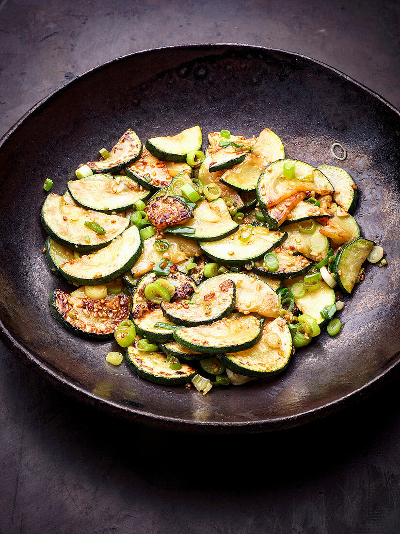 Gebratene Zucchinischeiben mit Frühlingszwiebeln im Wok (Asien)