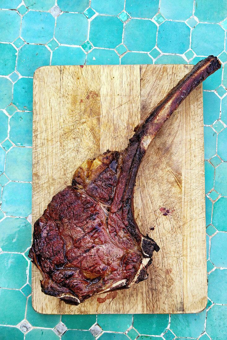 A grilled tomahawk beef steak on a wooden board (top view)