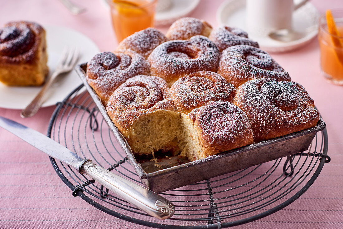 Cinnamon rolls in a square baking dish on a cooling rack