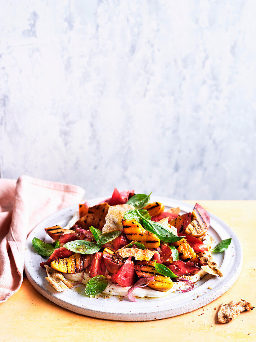 Salat mit gegrillten Pfirsichen, Tomaten und Fladenbrot mit Granatapfeldressing auf Frischkäse