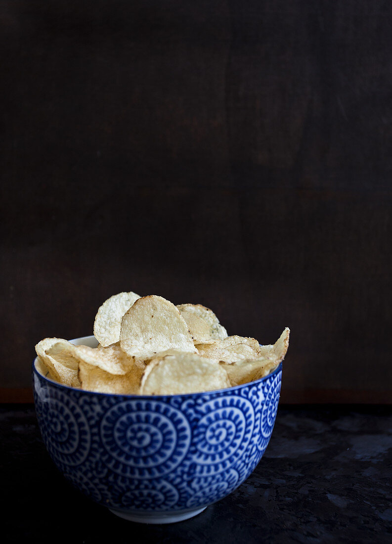 A blue and white bowl with chips, sitting on a dark countertop