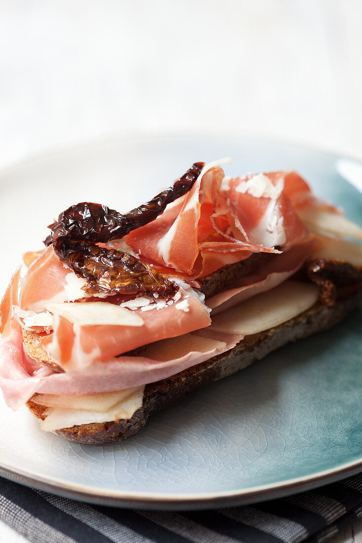 Belegtes Brot mit Parmesan, Birnen, rosa Radicchio, getrockneten Tomaten und Parmaschinken