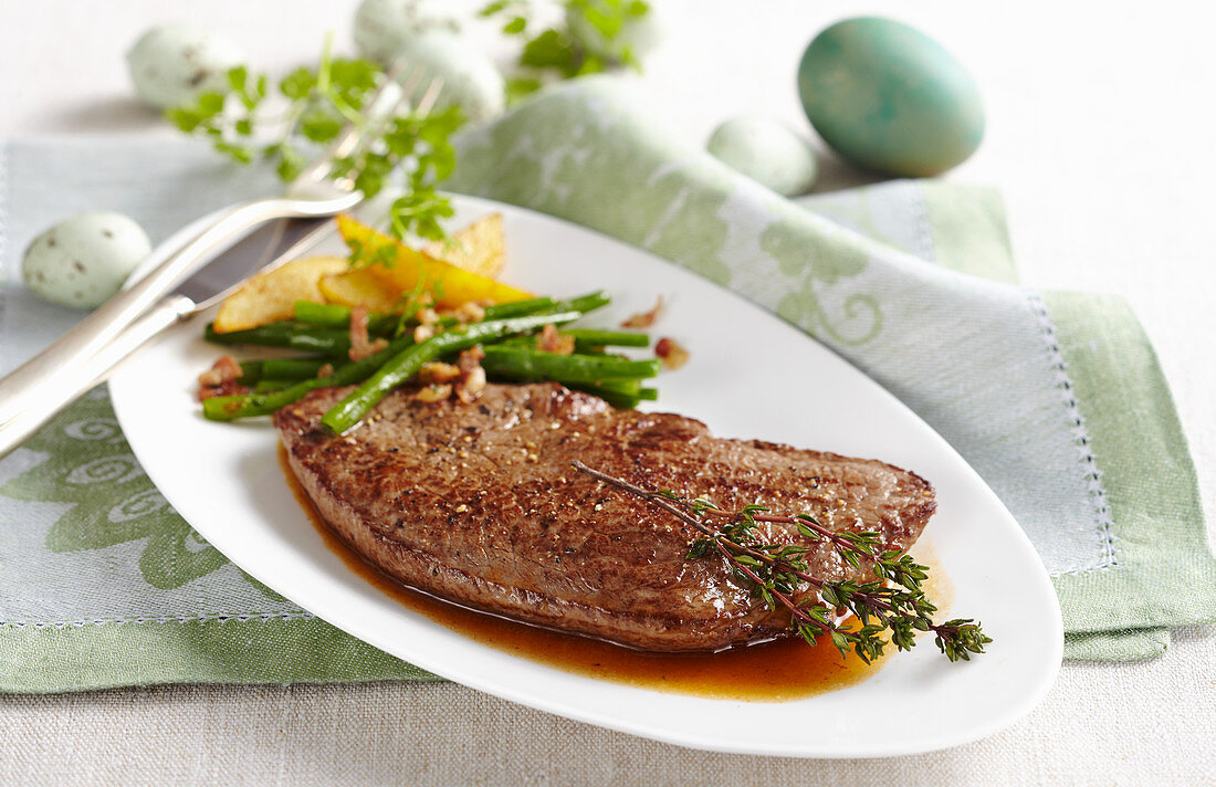 Gebratenes Rinderhüftsteak mit Bohnengemüse und Kartoffelspalten zu Ostern