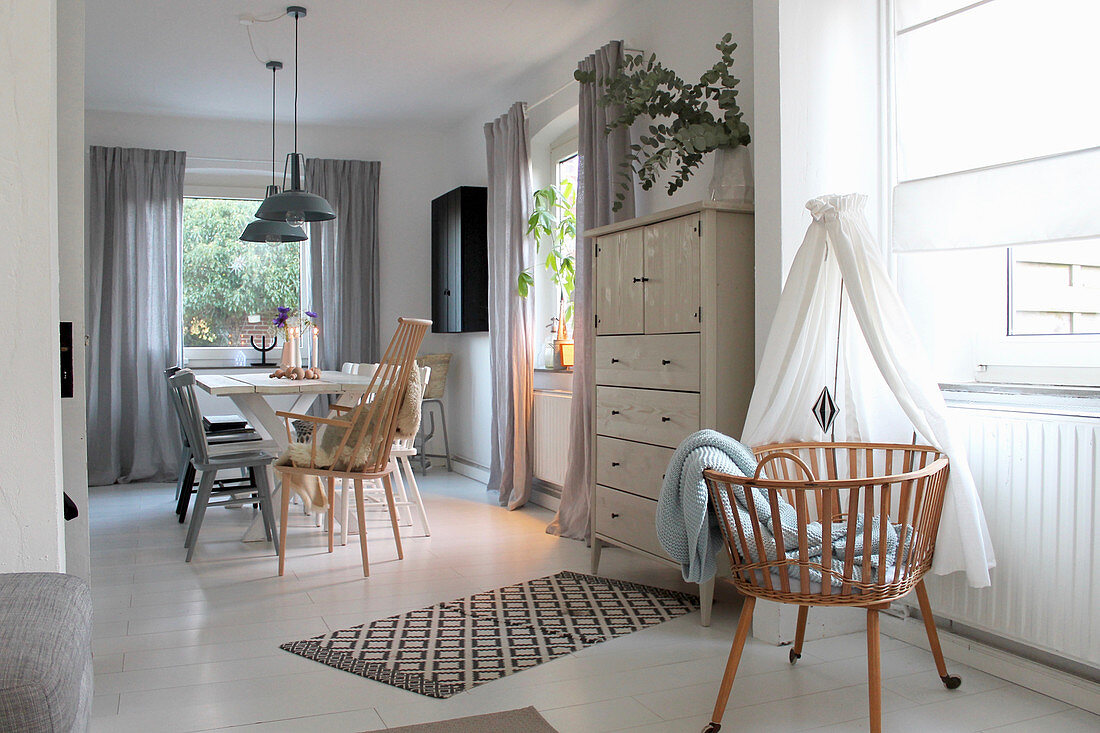 Bassinet and chest of drawers with dining area in background