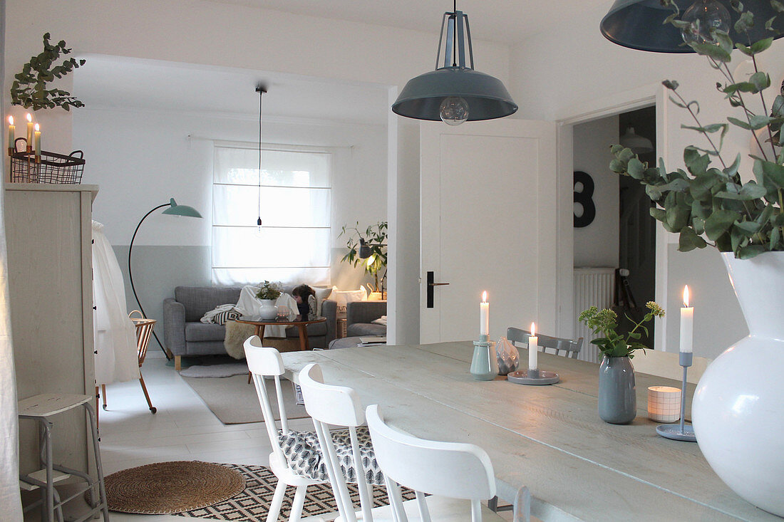 White wooden table and wooden chairs in open-plan interior