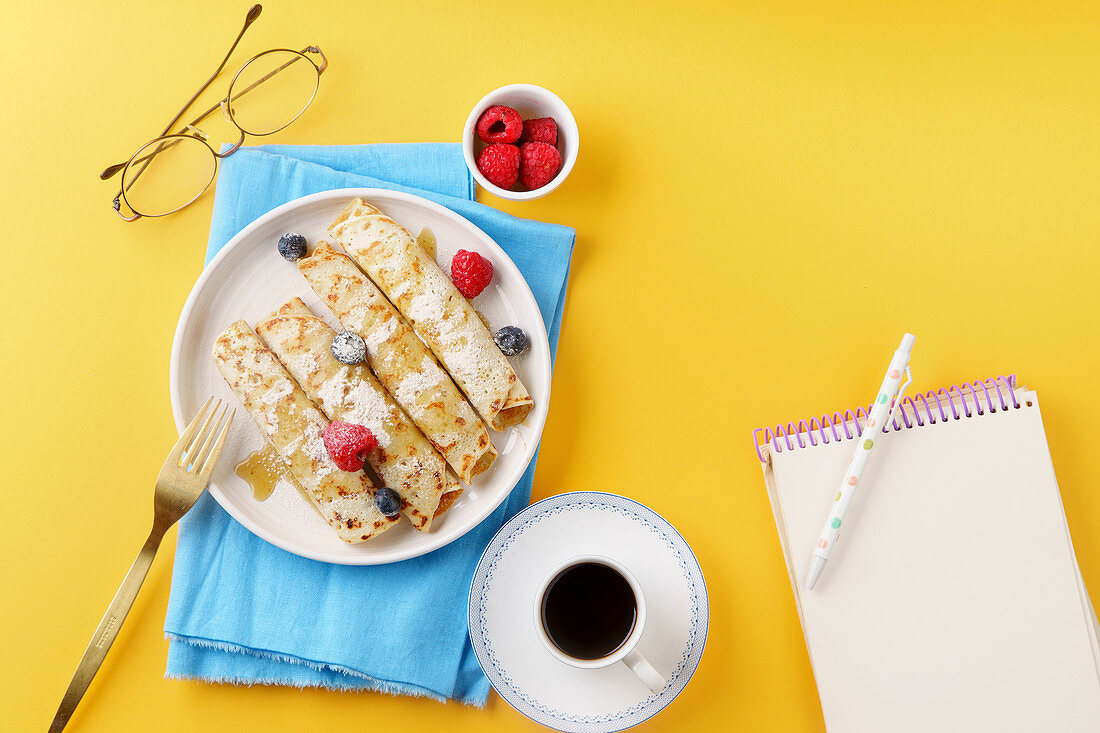 Rolled pancakes with blueberry and raspberry, caramel and powdered sugar