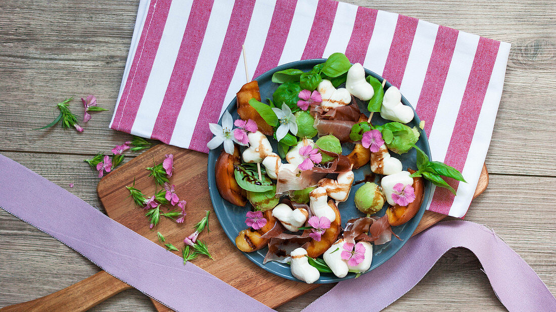 Summer salad with grilled peaches, ham, mozzarella hearts and basil