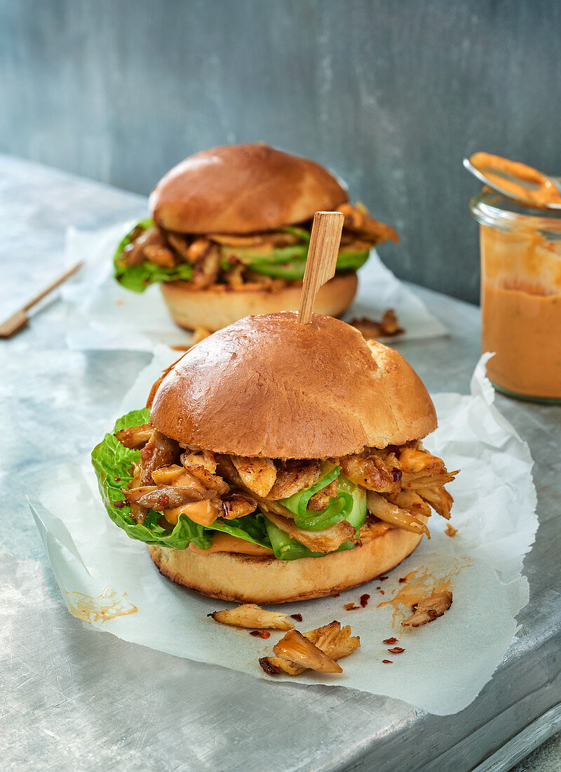 Two pulled chicken burgers on parchment paper
