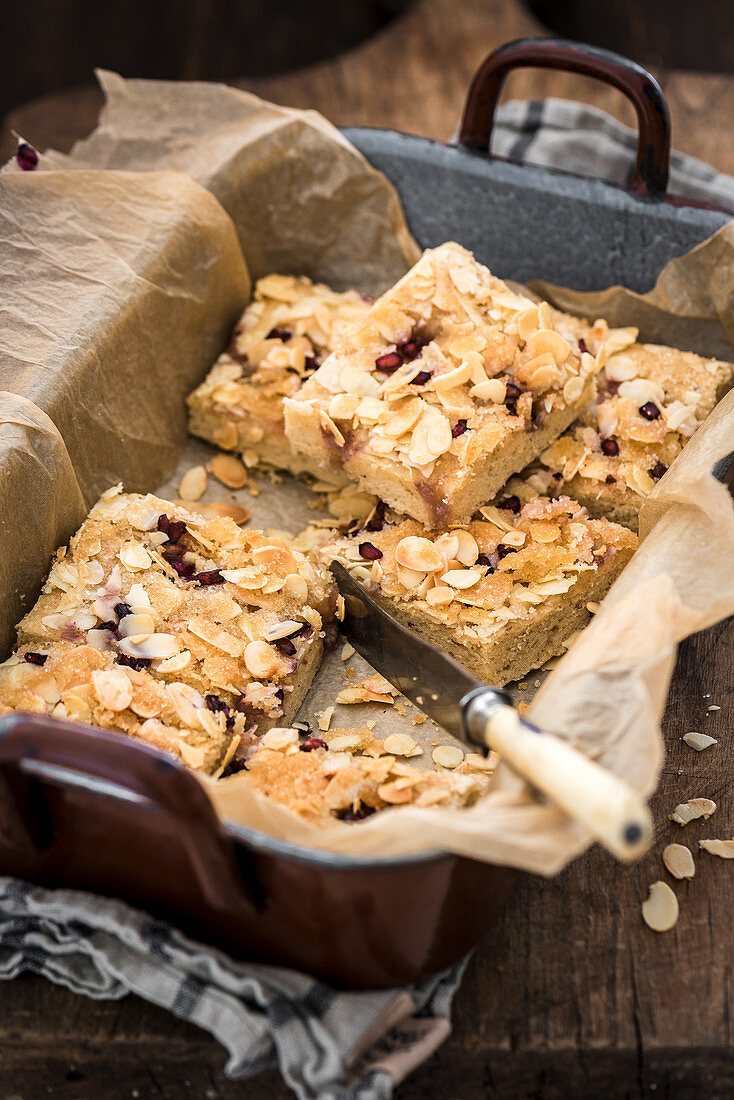 Butter cake slices with pomegranate seeds and flaked almonds