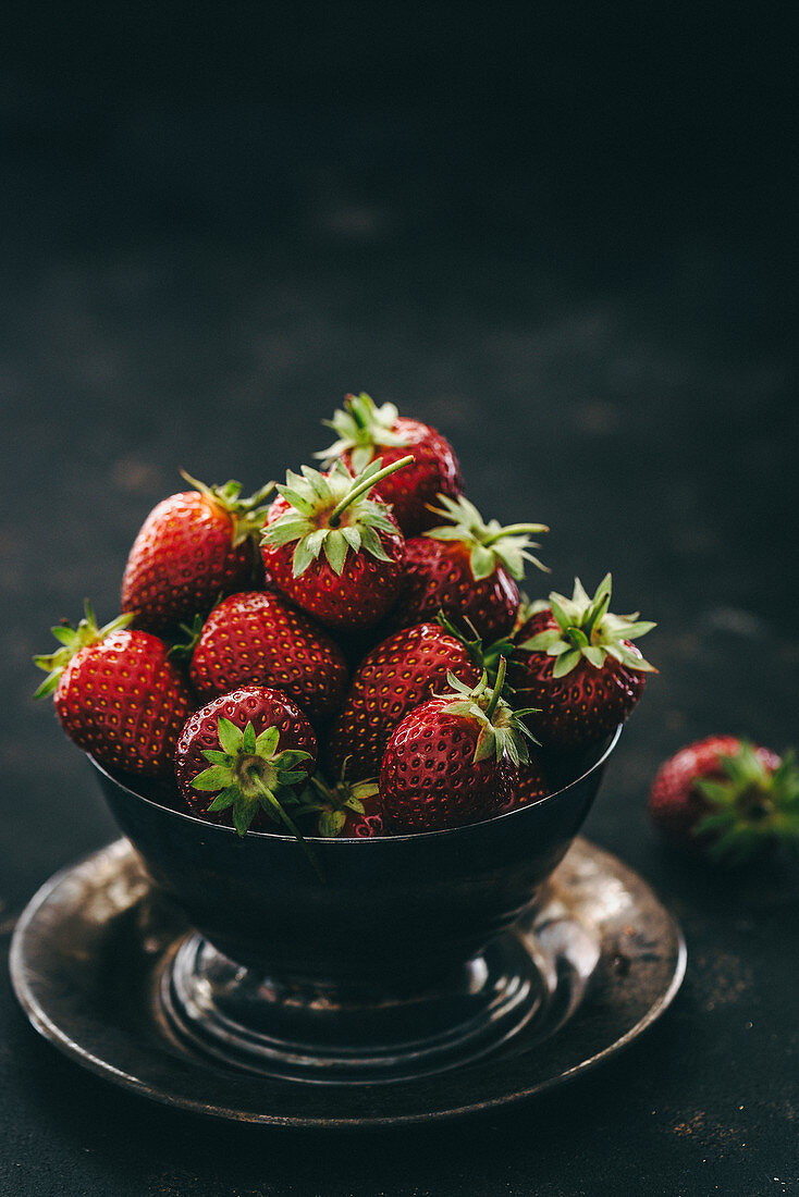 Strawberry in a metal bowl on a metal plate