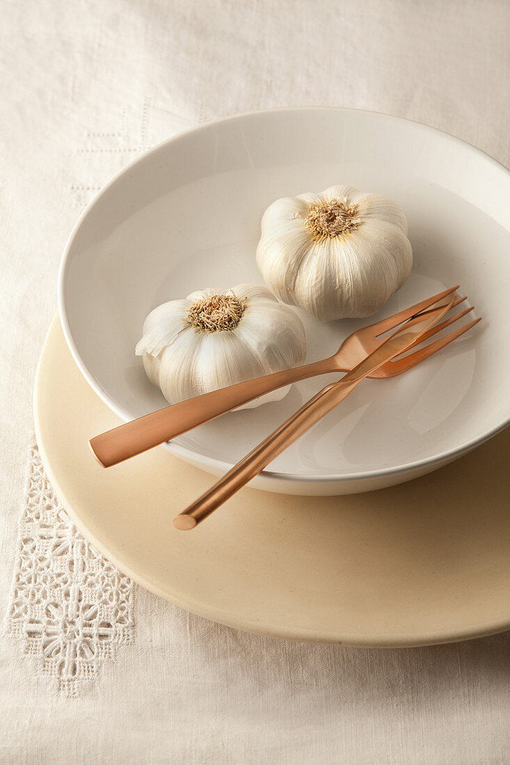 Fresh garlic and cutlery in bowl