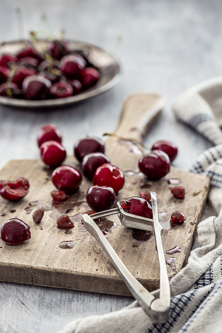 Cherry with a cherry pitter on a wooden board