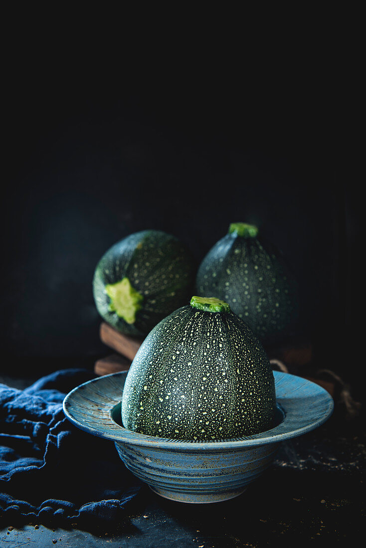 Raw round courgette on dark background