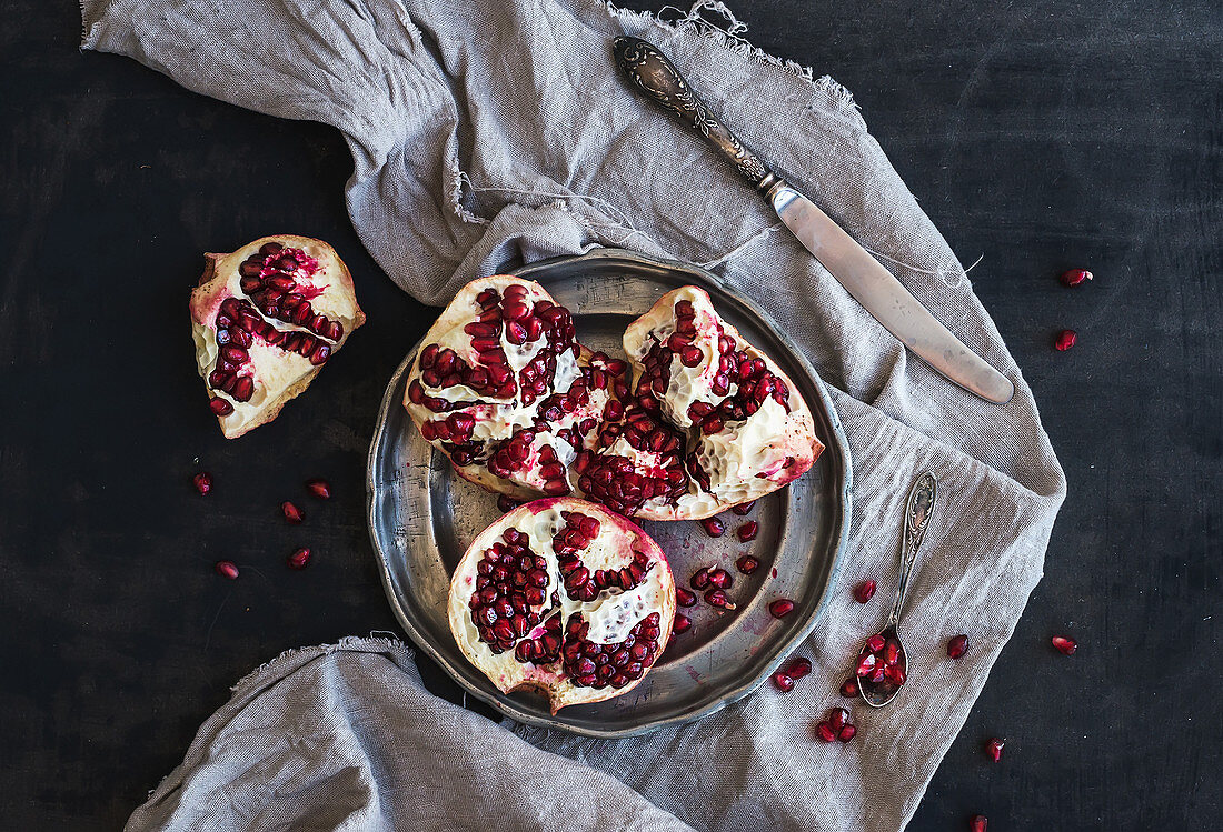 Red ripe peeled pomegranate on rustic metal plate