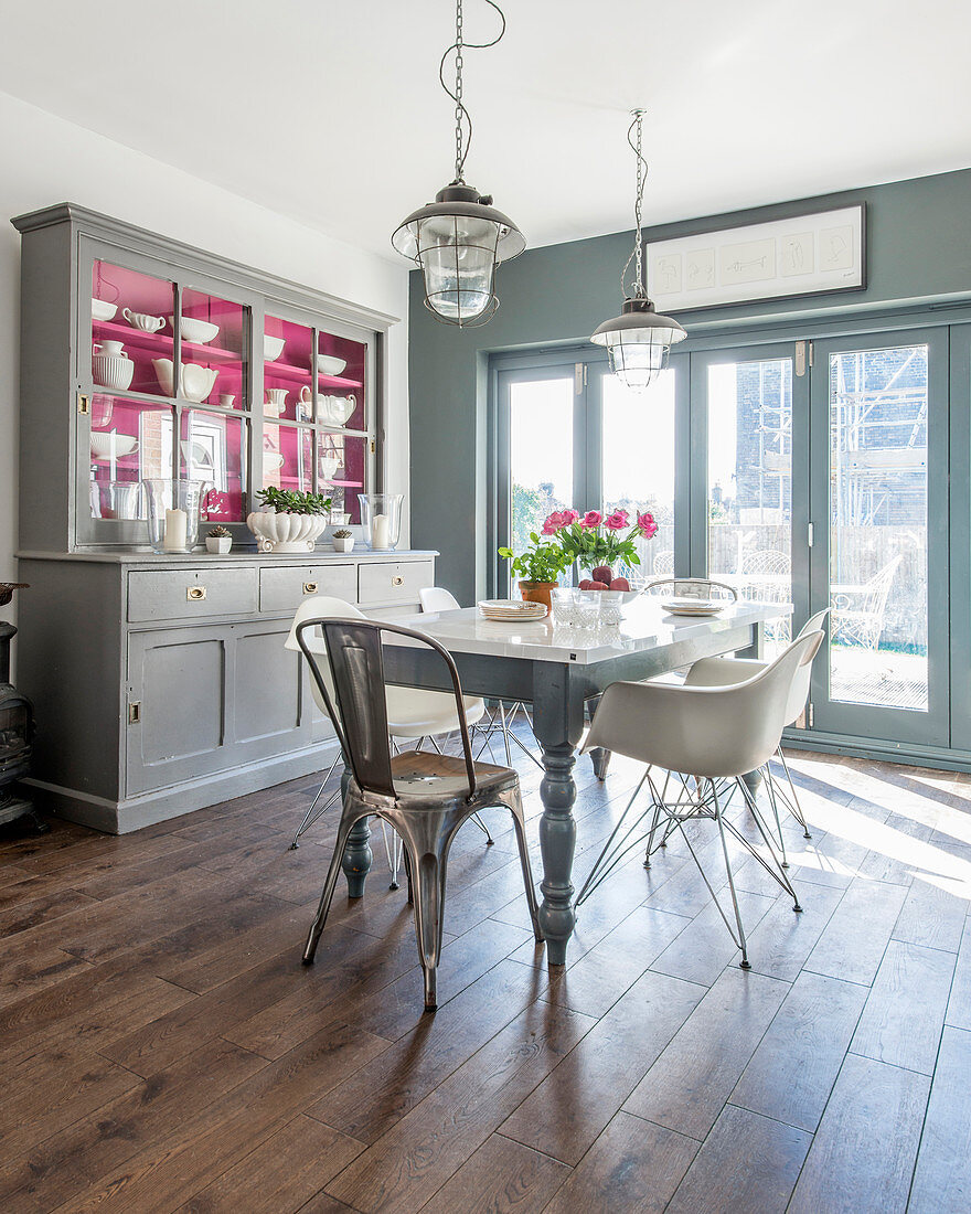 Küchenbuffet mit pinkem Innenleben im sonnigen Esszimmer in Grau