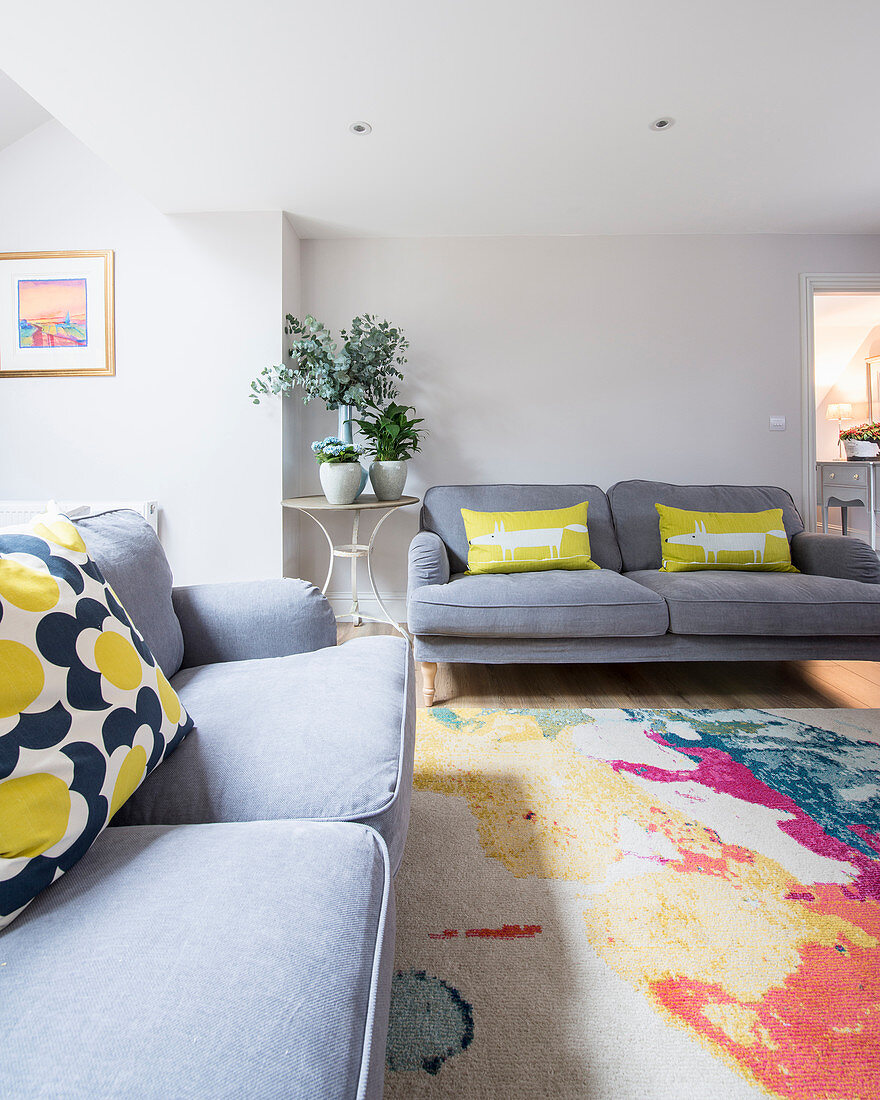 Colourful scatter cushions on grey sofas in simple living room