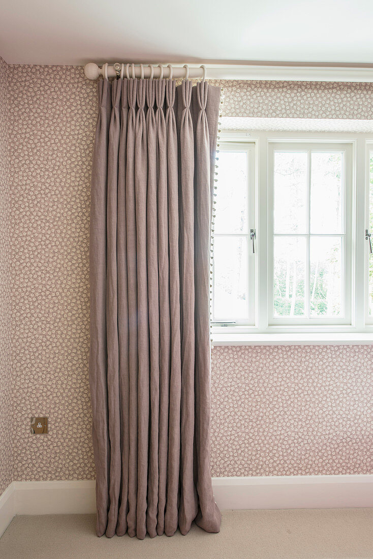 Grauer Vorhang mit eleganten Falten an gepunkteter Wand